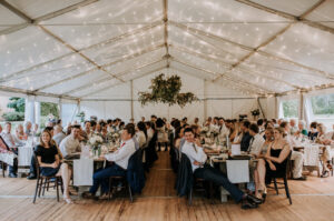 Guests under Hocker Marquee at Wedding Reception with Rustic Tables