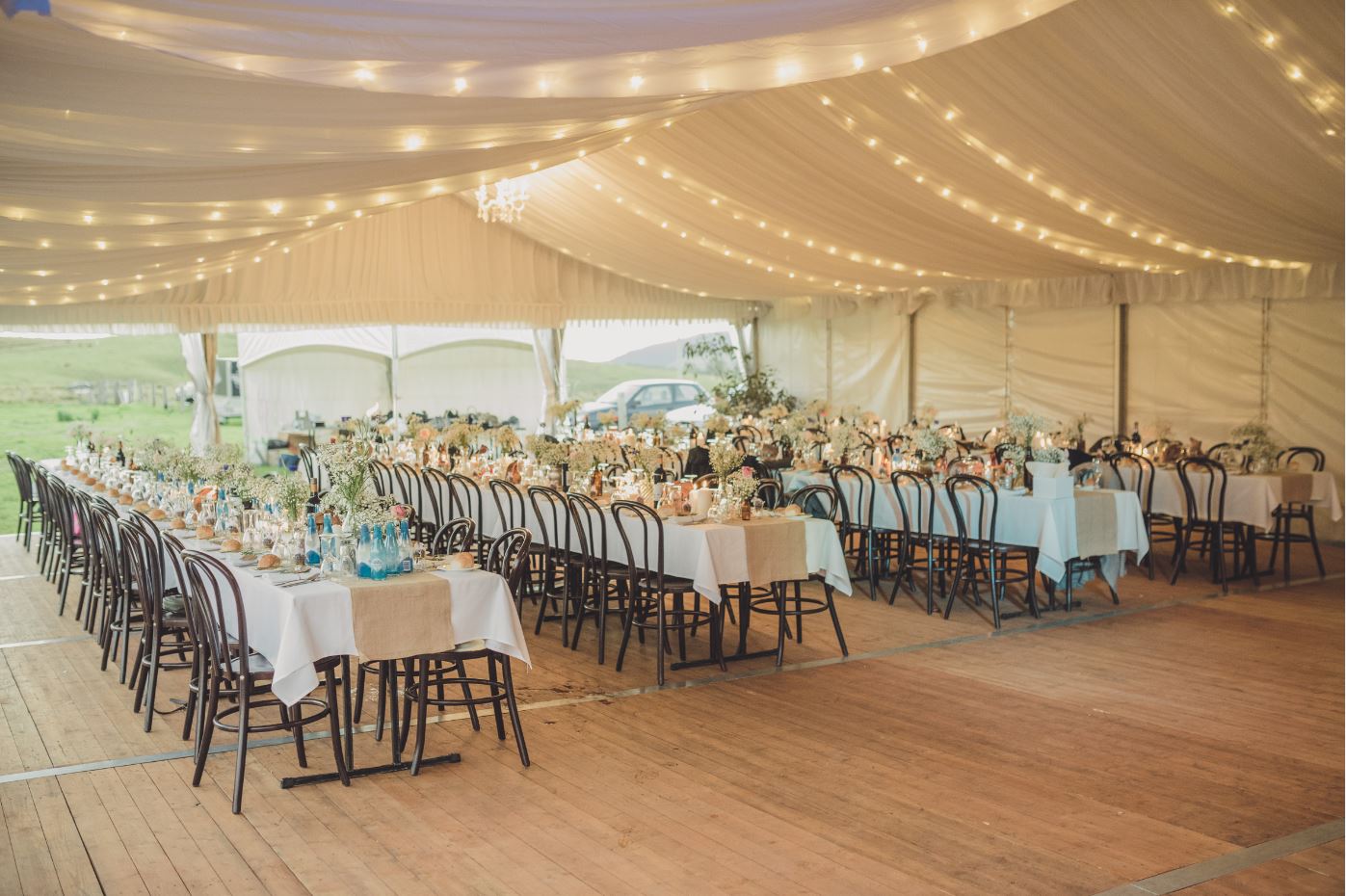 Wedding Reception Under Marquee with Hanging Silk Lining and Timber Bentwood Chairs