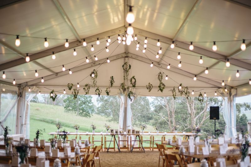 Festoon Lighting Under Hocker Marquee for Wedding Reception with Timber Dining Tables