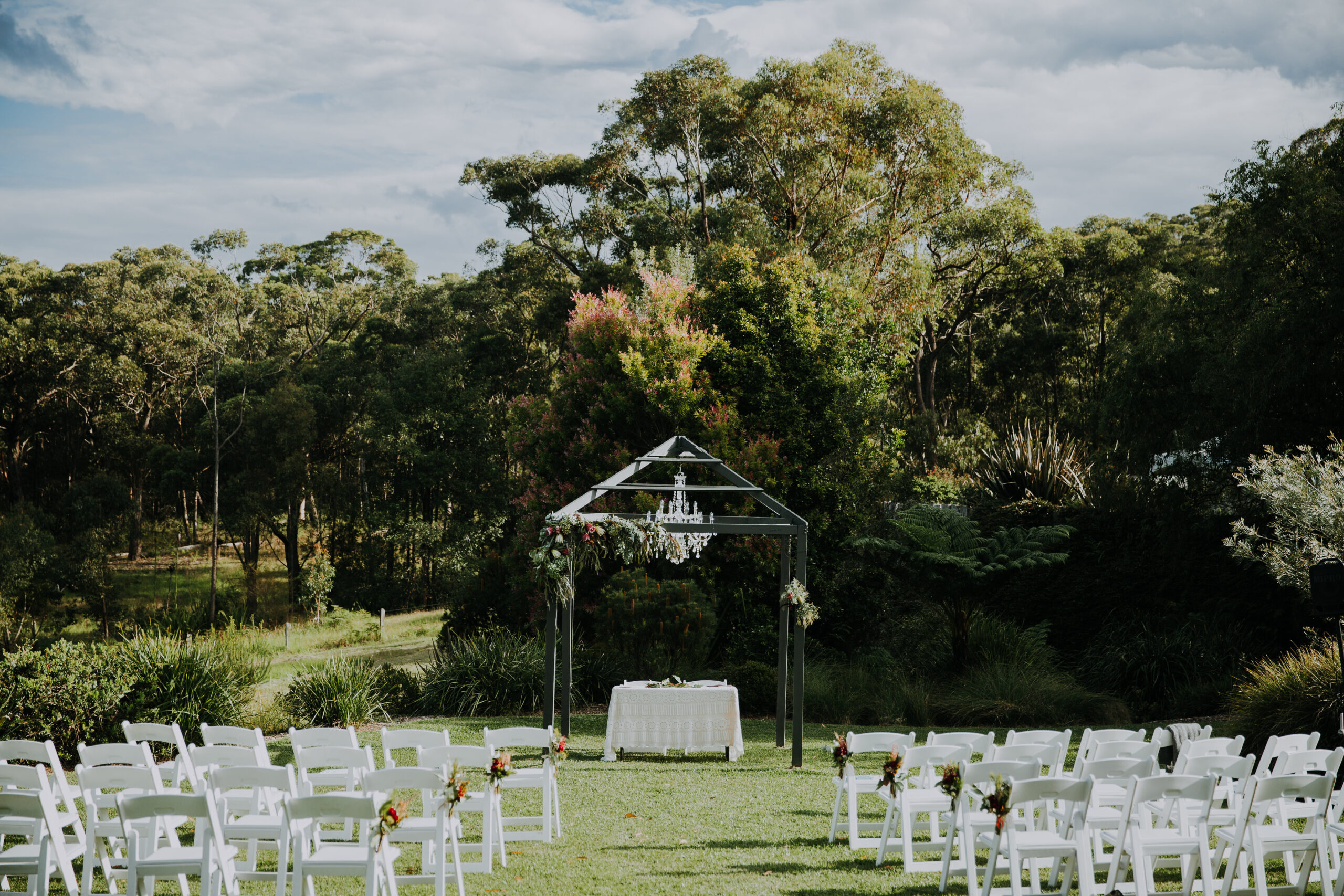 Wedding Ceremony with Arch and White Fold Up Chairs
