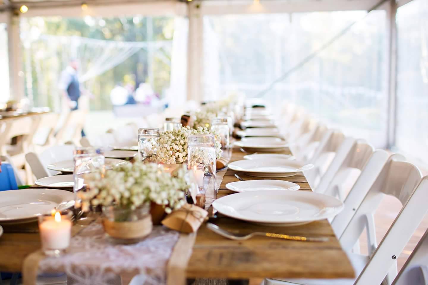 Rustic wedding table at reception with white fold up chairs.
