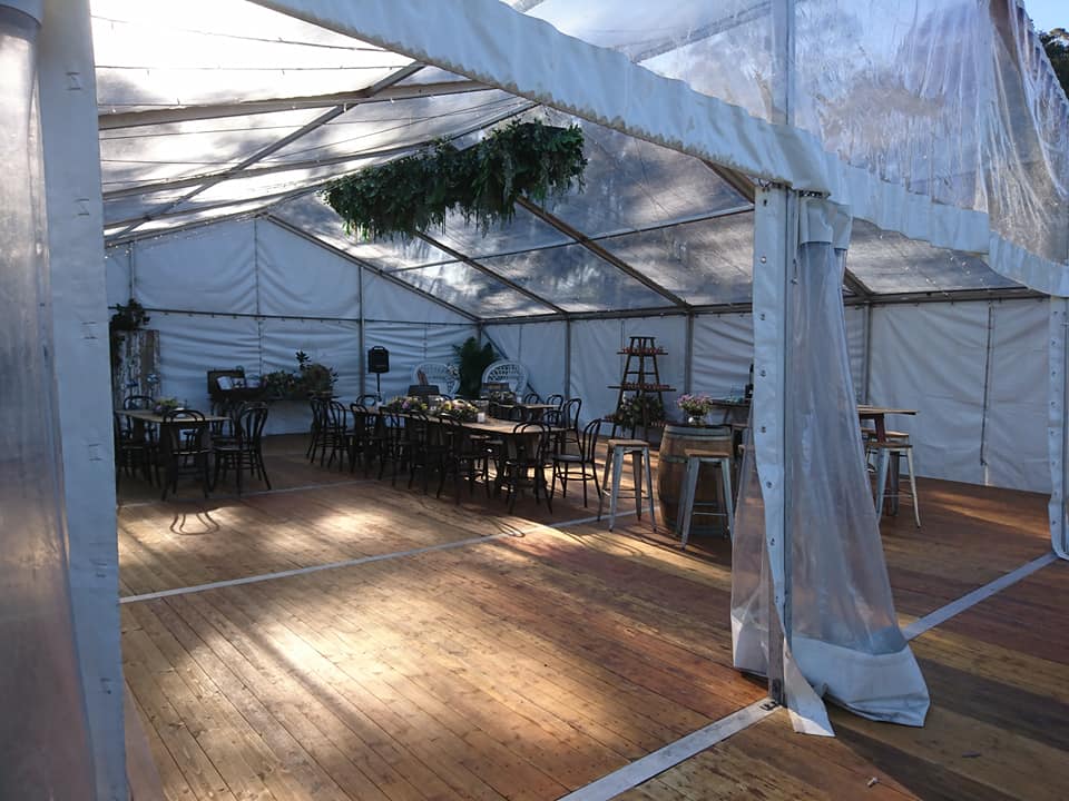 Clear marquee featuring integrated timber flooring with guest tables and chairs.